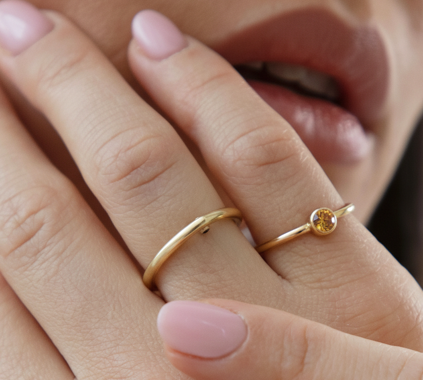 Close-up of a hand wearing the Citrine birthstone gold ring on the pinky finger. 